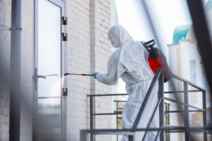 Coronavirus Pandemic. A disinfector in a protective suit and mask sprays disinfectants in the room. Protection of COVID-19 disease. Prevention of spreding pneumonia virus with surfaces we touch.